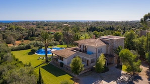 Une grande maison avec une piscine, entourée d’une végétation luxuriante et offrant une vue dégagée sur la mer.