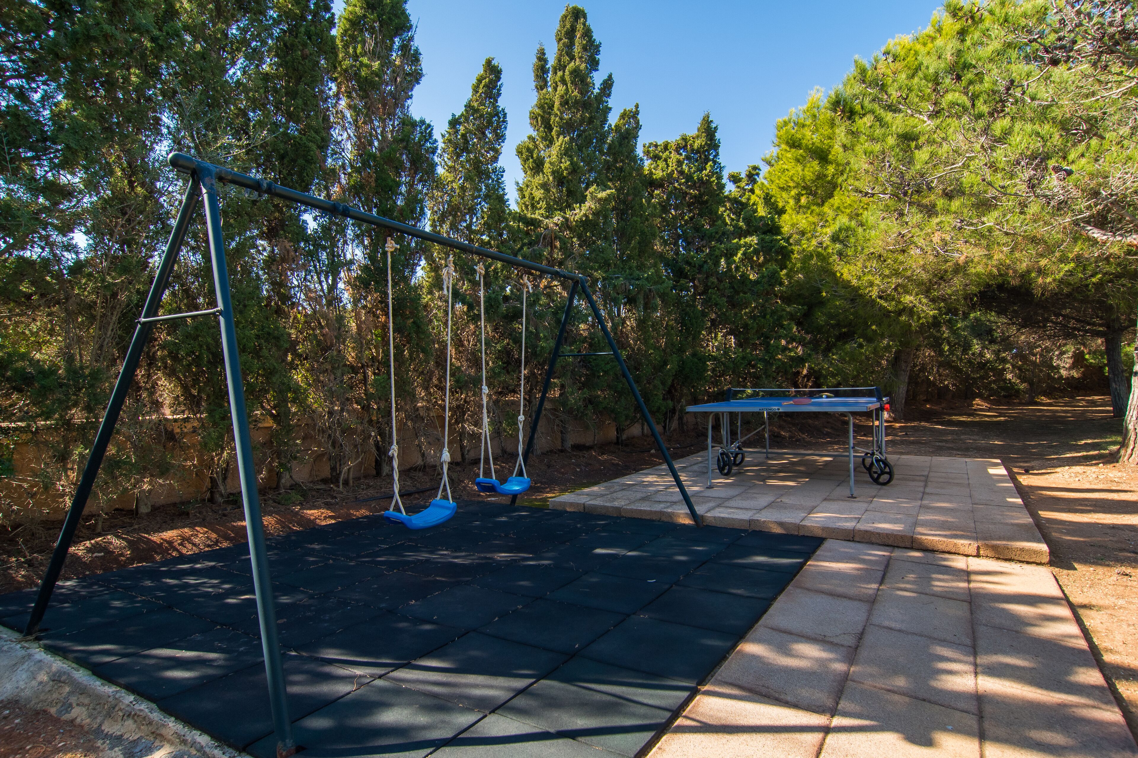 A playground with swings and a ping pong table.