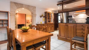 Une cuisine spacieuse avec des meubles de rangement en bois, une table à manger avec des chaises et un four encastré.