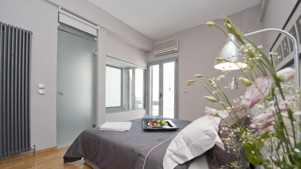 Un dormitorio moderno con una cama, una bandeja de fruta, una lámpara de noche y una ventana con vistas.