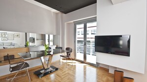 Una sala de estar moderna con un televisor grande, una mesa de comedor de vidrio y un sofá.