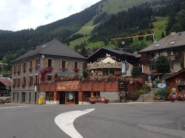 A hotel with a stone facade, a carousel, and flower boxes. - Chatel Centre - 50 M to Ski Lift (Châtel)