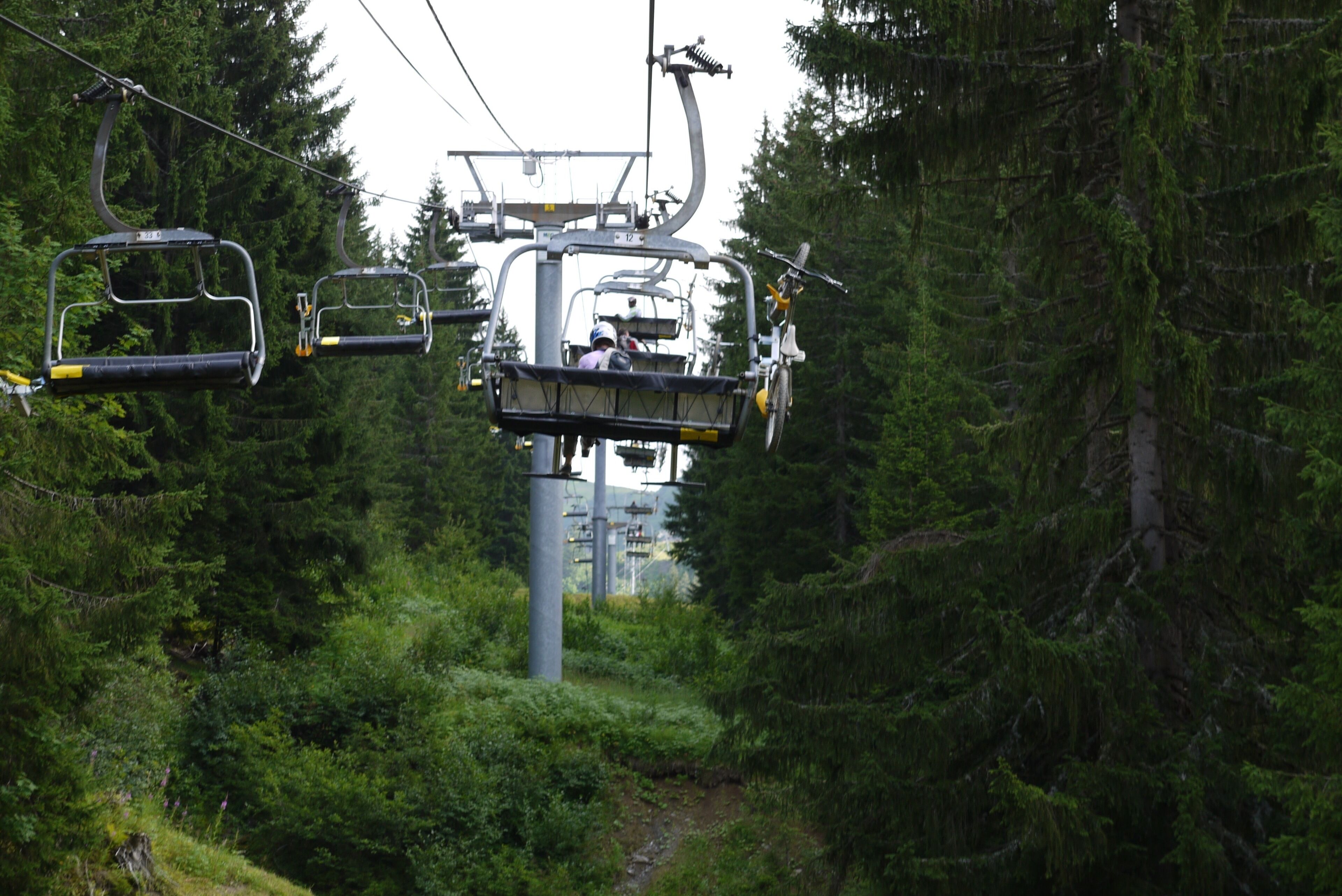 A ski lift in a forested area with multiple chairs.