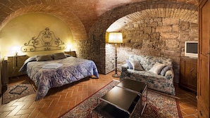 A cozy room with a bed, a sofa, a lamp, and a TV. - san gimignano apartment in historical center, courtyard and fast free wifi (San Gimignano)