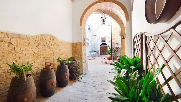 A narrow alleyway with brick walls, wooden barrels, and potted plants. - san gimignano apartment in historical center, courtyard and fast free wifi (San Gimignano)