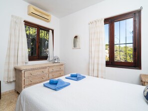 Relax in this cozy space with a large bed, wicker dresser, and small mirror.