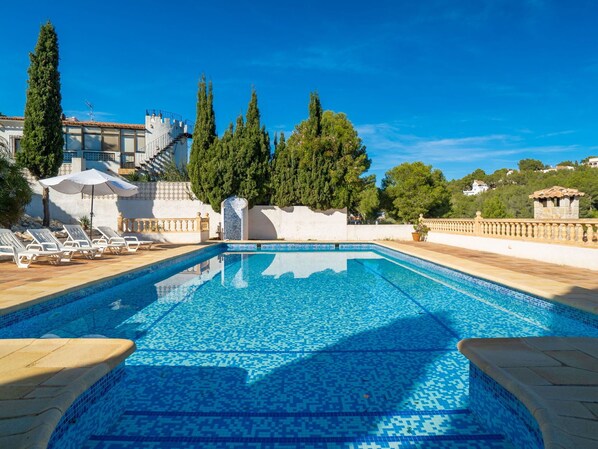 Relax by the serene pool surrounded by lush greenery and architectural elements.