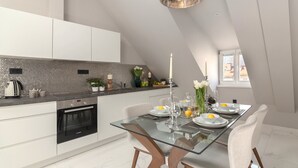 A modern kitchen with a glass dining table, white cabinets, and a built-in oven.