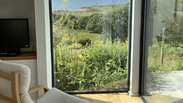 Ein modernes Wohnzimmer mit einem großen Fenster und Blick auf eine Küstenlandschaft.