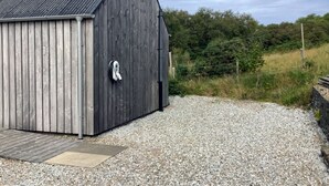 Ein Holzhaus mit Metall-Dach, einem Schotterweg und einem Holzsteg.