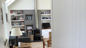 Ein modernes Wohnzimmer mit Kamin, Bücherregalen, einem Fernseher und einem Essbereich.