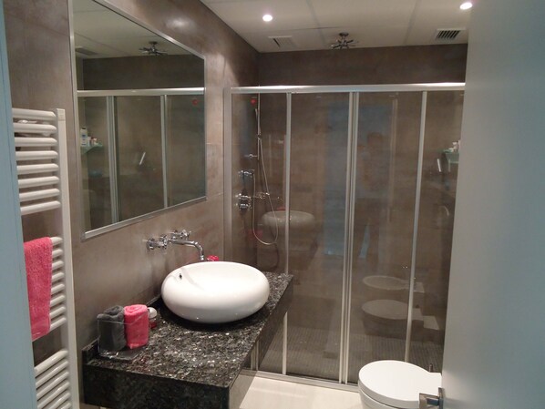 Une salle de bain moderne avec une douche à parois de verre, un lavabo blanc et un grand miroir.