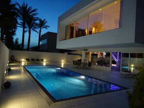 Une maison moderne dotée d’une piscine, d’un espace salon extérieur et d’un escalier menant à un balcon.