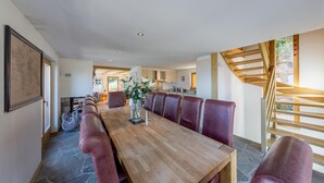A dining area with a long wooden table, red upholstered chairs, and a vase with flowers. - Beautiful chalet in the Swiss Alps with stunning views and private hot tub  (Haute Nendaz)