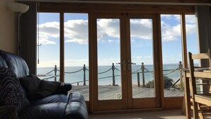 A room with a large window overlooking a scenic view of the sea and a wooden deck. - 5 Star Luxury barn conversion overlooking the sea in North Wales (sleeps 2) (Barmouth)