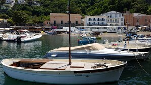 Un puerto deportivo con barcos amarrados, un edificio con el letrero 'Le Axide' y una ladera con edificios al fondo.