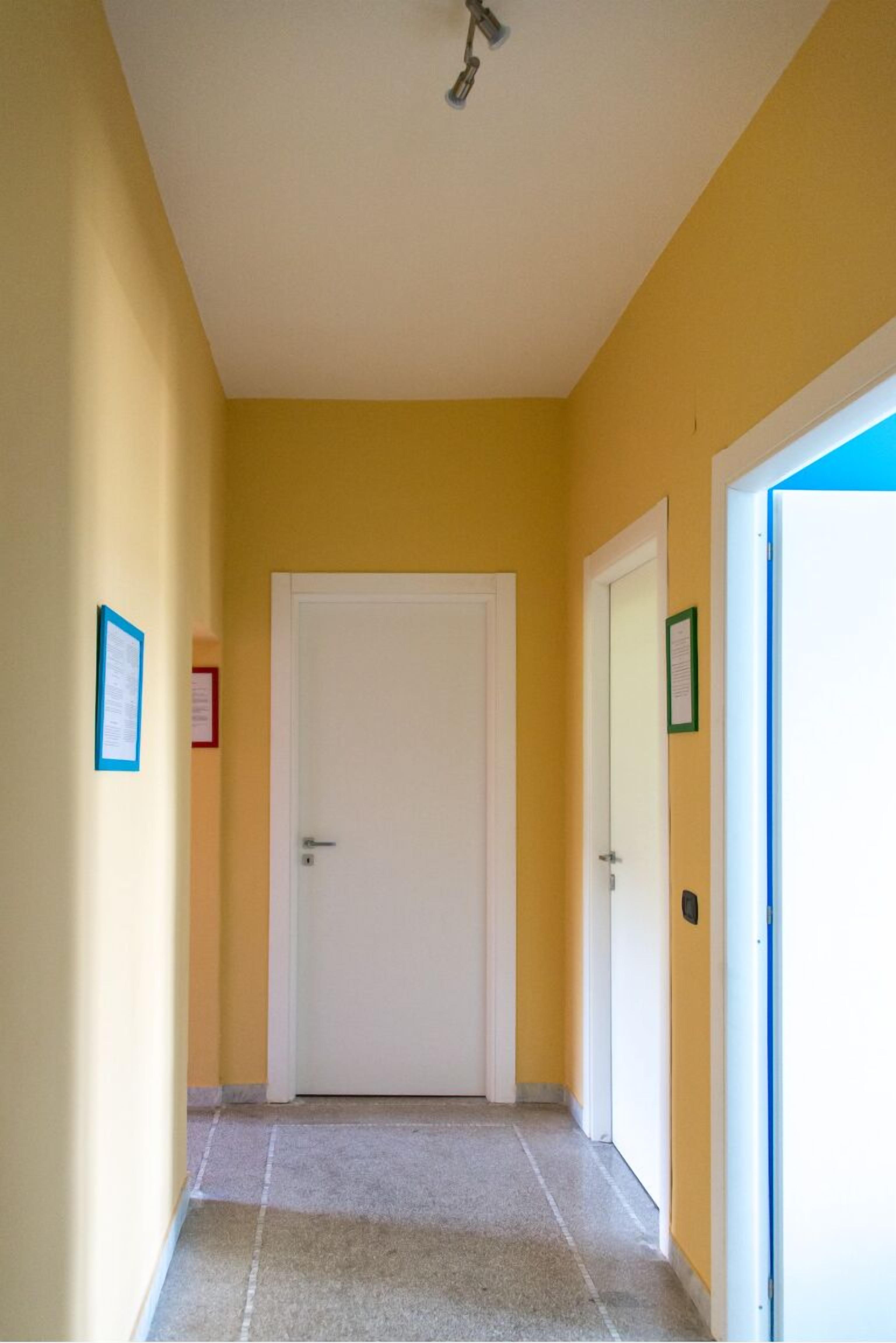 A hallway with yellow walls, white doors, and a ceiling light fixture.