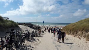 En sandstig som går längs stranden, med cyklar parkerade på vänster sida, och som leder ner till stranden.