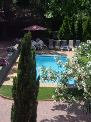 Una piscina envoltada per un jardí amb gespa, algunes cadires i una taula.