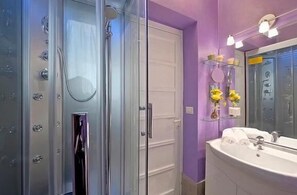 A bathroom with a glass shower enclosure, a white sink with a mirror, and purple walls. - Rome: House with character. In the center of Rome. near the Vatican (Roma)