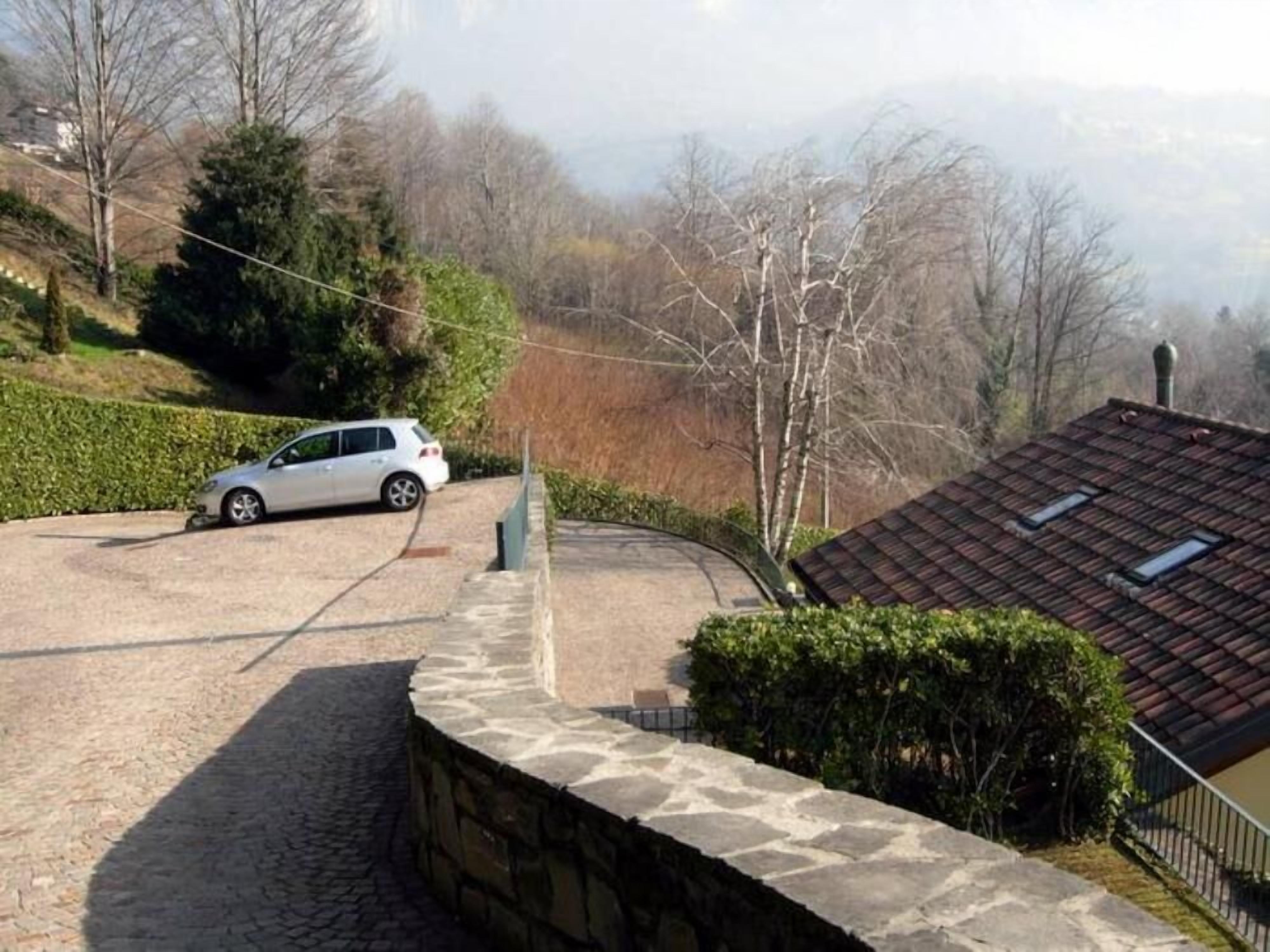 A stone wall, a parked car, and a house with a tiled roof.