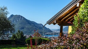 A view of a mountain with a town in the valley below, a clear sky, and a building with a wooden roof. - House / Villa - Lecco (Lecco)