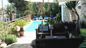 Zona de piscina con sillones de descanso y una sombrilla.