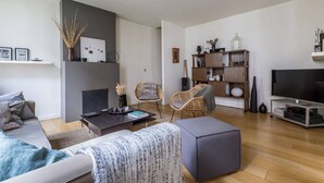 Een moderne woonkamer met een bank, een salontafel, een open haard, een boekenkast en een televisie.