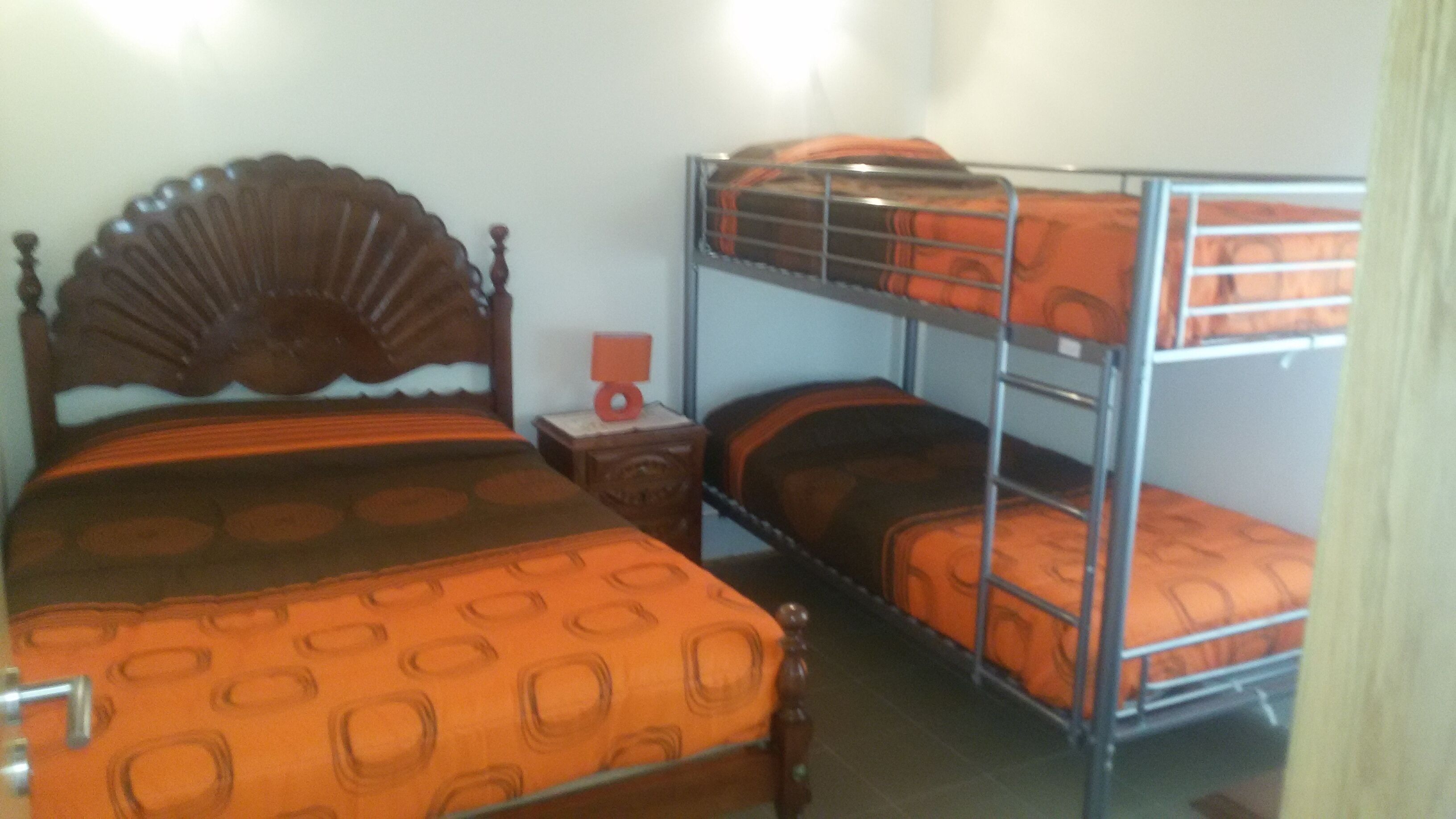 Une chambre avec un lit simple, une table de chevet et un lit superposé.