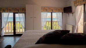 A bedroom with a bed, a television on the wall, and a balcony with a view of the sea. - Casa Charo with spectacular views of the sea (Cuchía, Miengo)