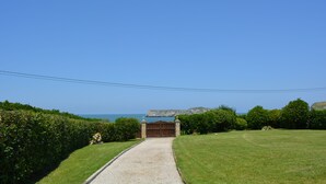 A pathway leading to a gated entrance with a view of the sea and a rocky cliff in the background. - Casa Charo with spectacular views of the sea (Cuchía, Miengo)