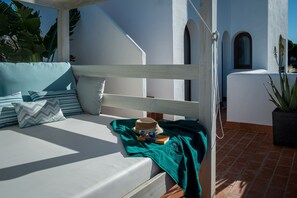 A sunlit outdoor seating area with a white bench, cushions, and a hat. - Entre Pinos. Modern Andalus, beach access and views (Roche)