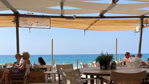 A wooden deck with outdoor seating, a sign reading "Sea Tour," and a view of the sea. - Luxury apartment, UK TV and free WIFI. Near beach and restaurants, pool view   (Paphos)