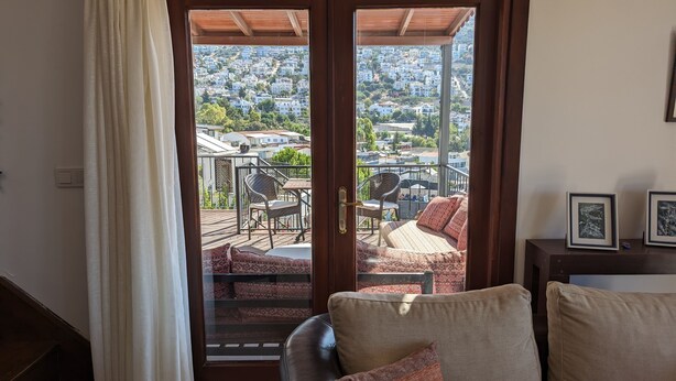 Ein Zimmer mit einer Schiebetür, die auf einen Balkon mit Blick auf eine Wohngegend führt.