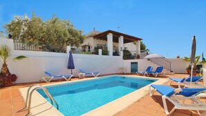 A swimming pool with blue lounge chairs and a covered patio area. - 1003 Villa Cornocalejo (Nerja)