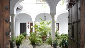 Une cour intérieure agrémentée d’arcades, de plantes en pot et d’un sol en briques.