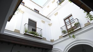 Un bâtiment blanc doté de balcons, de portes en arc de cercle et de plantes suspendues.