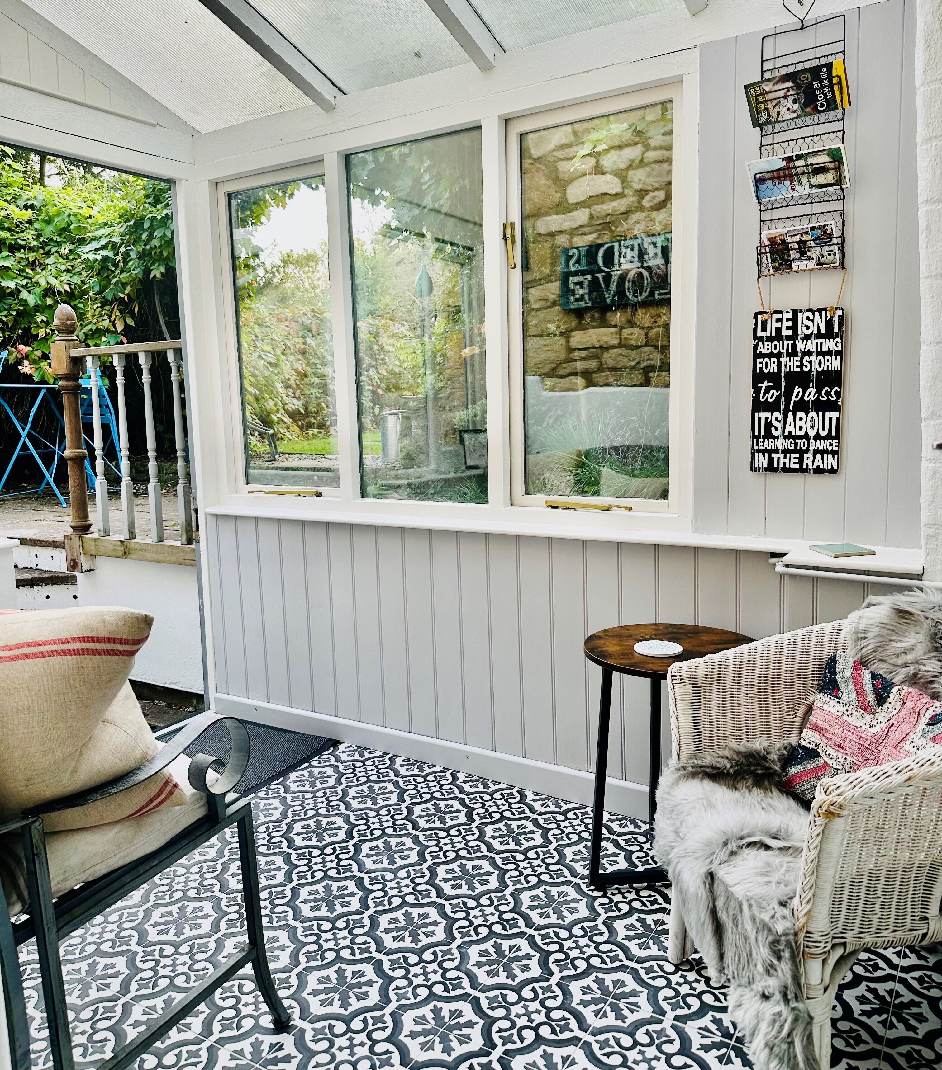 Une pièce chaleureuse avec un sol à motifs, une chaise en osier, une petite table et un chien.