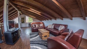 A spacious attic room with wooden beams, leather sofas, a wooden coffee table, and a television. - A/C 4 bedroom Villa, Pool, sea views beach 6 minutes walk.  Sleeps 8 people. (Pula)