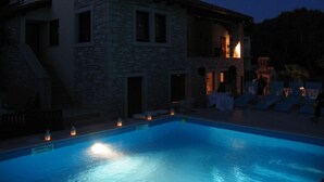 A stone building with a swimming pool at dusk. - A/C 4 bedroom Villa, Pool, sea views beach 6 minutes walk.  Sleeps 8 people. (Pula)