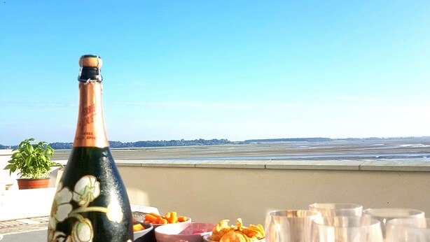A bottle of champagne, a basket of snacks, and empty glasses on a table with a view of the beach. - Beautiful 4* villa on the sand, feet in the water, stunning bay views (Le Crotoy)