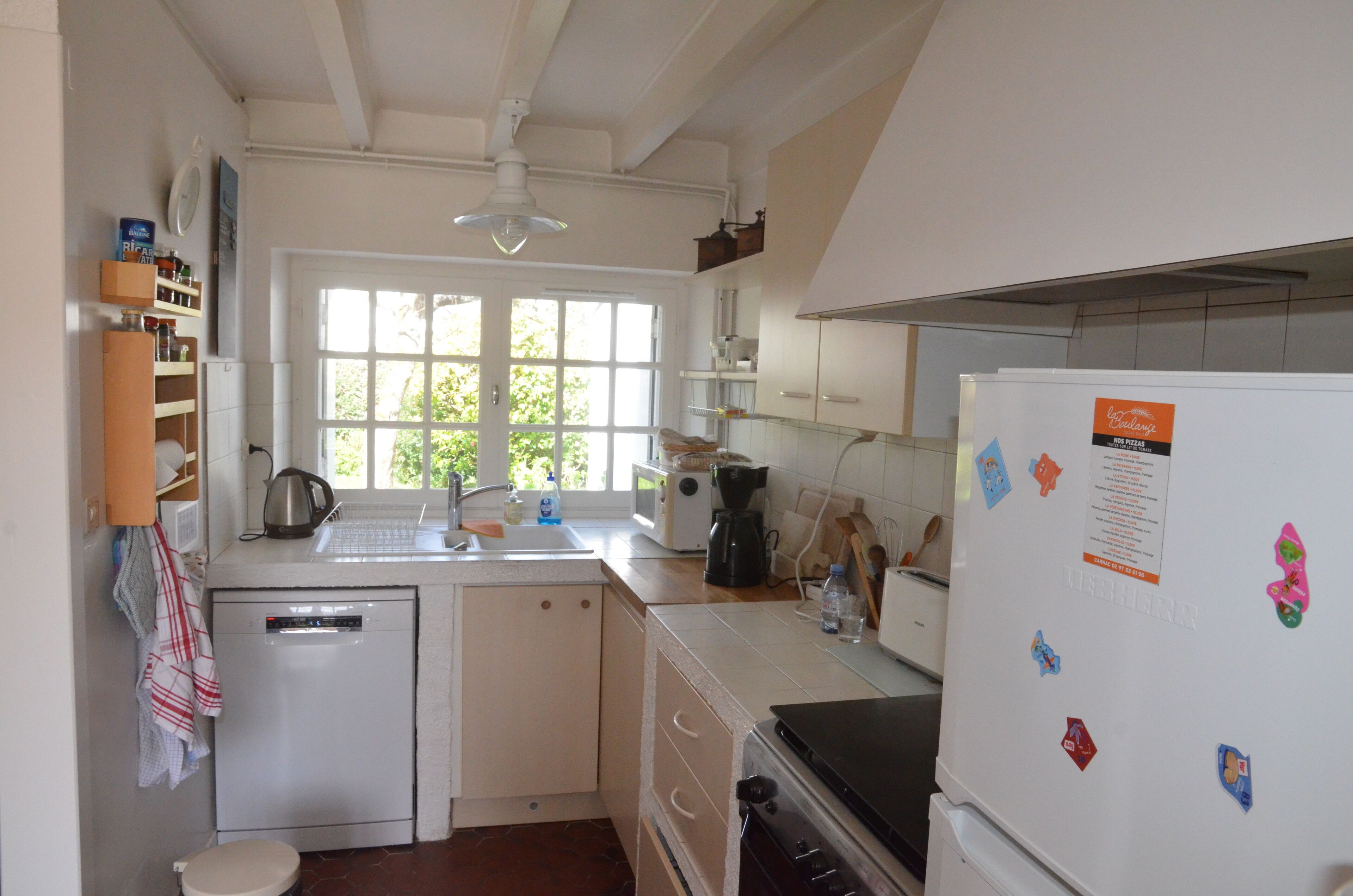 A kitchen with a dishwasher, a refrigerator, a window, and a sink.