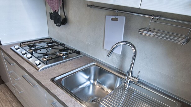 Une cuisine moderne dotée d’appareils électroménagers en acier inoxydable, d’un évier à deux bacs et d’un revêtement de sol en bois.
