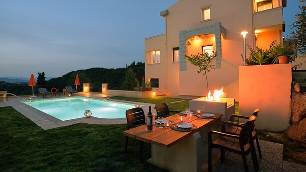 Ein modernes Haus mit Schwimmbad, Essbereich im Freien und einer gut beleuchteten Terrasse.