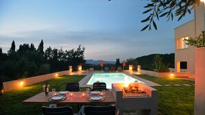 Ein Essbereich am Pool mit einem Tisch für vier Personen, umgeben von Stühlen und einem Grill.
