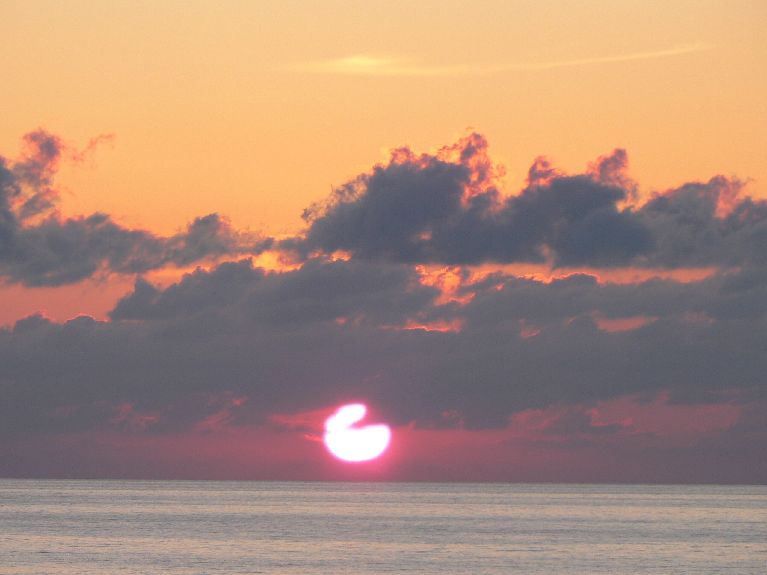 Tramonto sull'oceano con nuvole nel cielo.