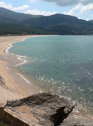 A beach with clear turquoise water, a sandy shore, and rocky outcrops. - Apartment in holiday residence with pool and beach (Calcatoggio)