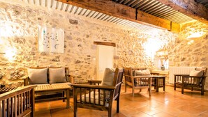 Um quarto rústico com paredes de pedra e mobiliário de madeira, incluindo um sofá, cadeiras e uma mesa.
