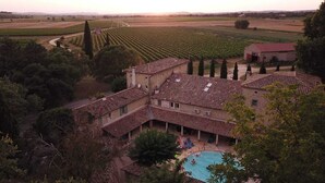 Uma villa com piscina, rodeada por vinhedos e árvores.