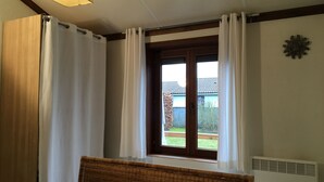 Un dormitorio con cama, ventana con cortinas, aire acondicionado de pared y viga de techo de madera.